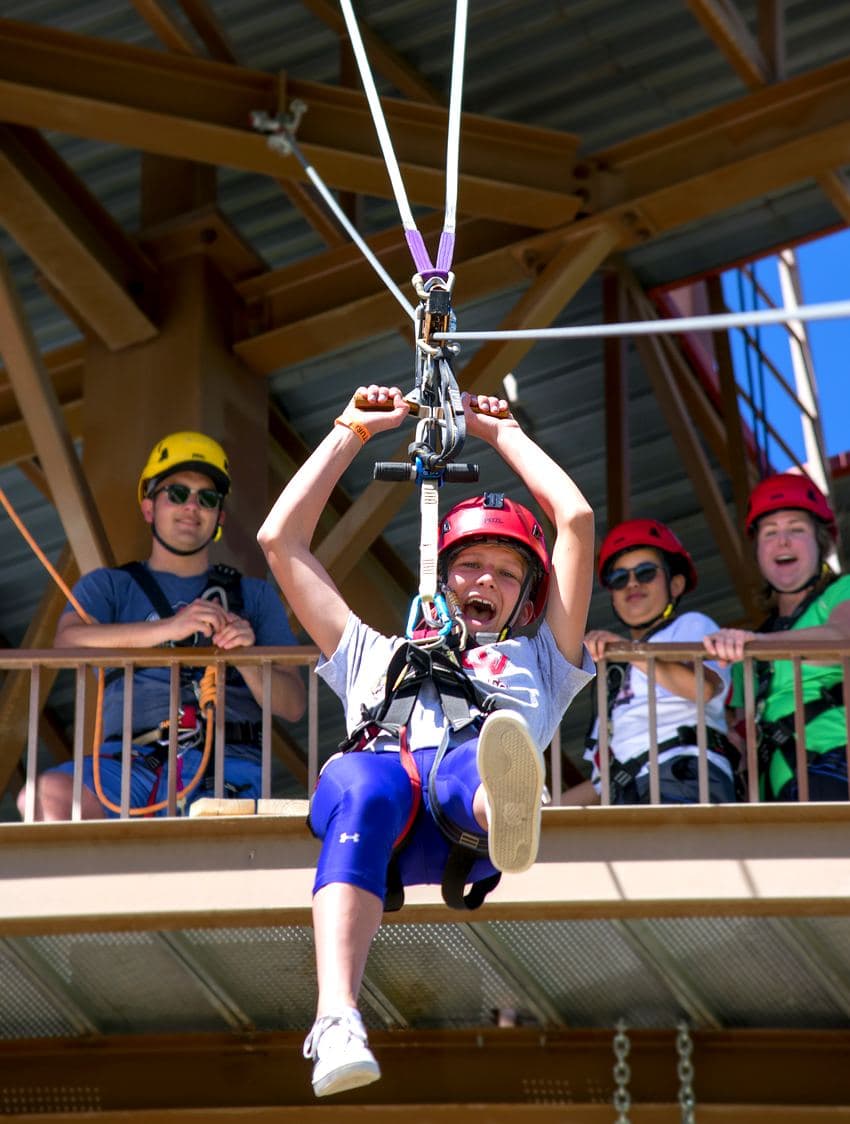 Kid launching off the Adventure Tower zipline with friends cheering